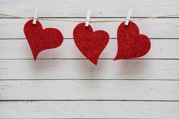 Red heart paper cut with natural cord and white clips hanging on the wall, valentines day.