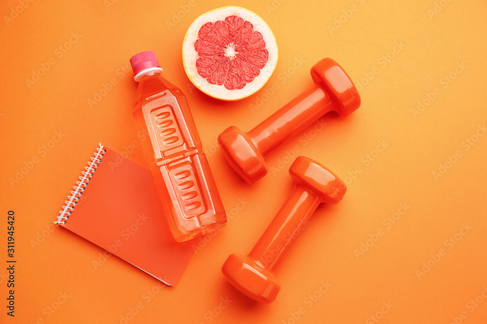 Wall mural dumbbells with notebook, grapefruit and bottle of water on color background