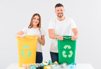 Couple with containers for garbage on light background. Concept of recycling