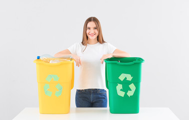 Woman with containers for garbage on light background. Concept of recycling