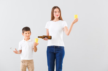 Thoughtful mother and son with different garbage on light background. Concept of recycling