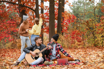 Happy young friends resting together in autumn park