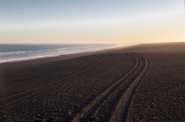 Fototapeta na wymiar Late afternoon. Ocean beach with tire track in the sand.Akaroa, New Zealand.