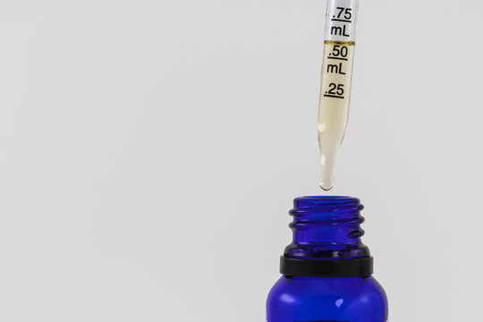 Cannabidiol Or CBD and THC oil being measured out of blue bottle with a pipette dropper studio shot isolated on white background Copy Space 