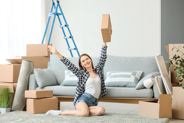 Happy young woman with moving boxes in new house