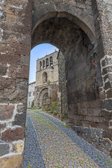 Naklejka premium The entrance to Arlempdes medieval village, the paved walk pass guides to Saint-Pierre roman church, Haute-Loire in France,