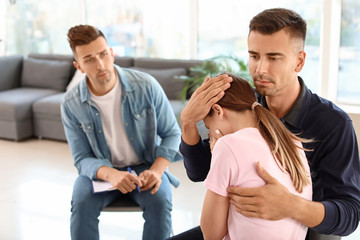 Man calming sad woman during psychological support session
