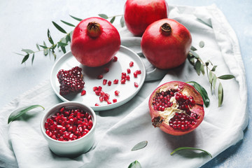 Tasty pomegranate with leaves on light background
