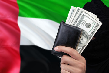 United Arab Emirates security and crime concept. Black criminals wear a head yarn, hold a dollar...