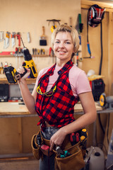 Young handy woman with short blond hair working with screwdriver.