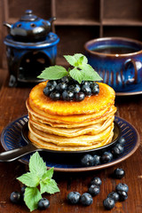 Pancakes with blueberry on ceramic plate  and tea cup