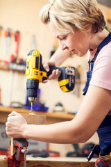 Young handy woman with short blond hair working with screwdriver.