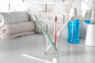 Holder with tooth brushes on table in bathroom
