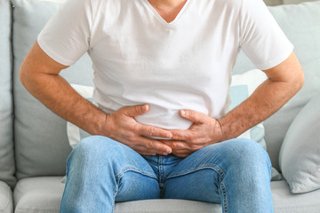 Mature man suffering from abdominal pain at home