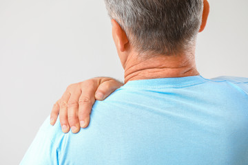 Mature man suffering from pain in shoulder on white background