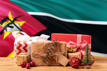 Mozambique new year celebration theme. Wrapped christmas gifts on waving national flag background....