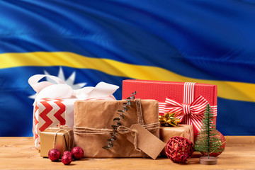 Nauru new year celebration theme. Wrapped christmas gifts on waving national flag background. Merry...