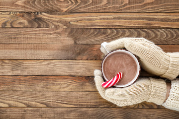 Female hands with cup of hot chocolate on wooden background