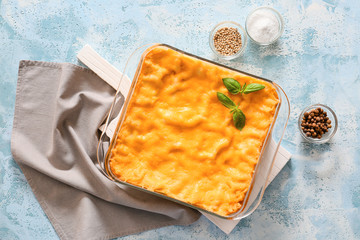 Baking dish with prepared lasagna on color background
