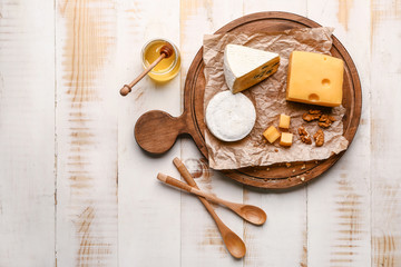 Assortment of fresh cheeses with honey on wooden table