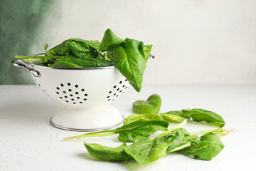 Colander with fresh green spinach on table