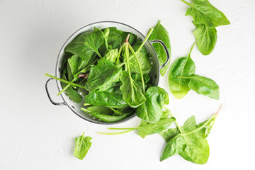 Colander with fresh green spinach on table
