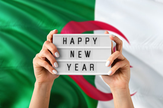 Algeria New Year concept. Woman holding Happy New Year sign with hands on national flag background. Celebration theme.