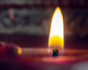a single yellow orange glowing candle with a blurred bokeh background with copy space