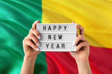 Benin New Year concept. Woman holding Happy New Year sign with hands on national flag background....
