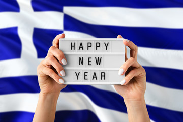 Greece New Year concept. Woman holding Happy New Year sign with hands on national flag background. Celebration theme.