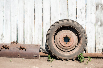 Tractor wheel and other tractor details against wooden rural fence background