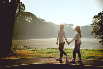 Asian Couple hold hand together￼. They are walking and talking cheerfully on morning with sepia...