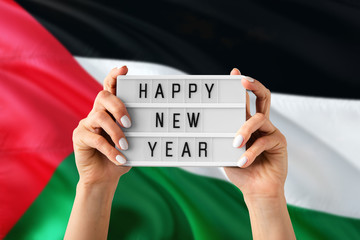 Palestine New Year concept. Woman holding Happy New Year sign with hands on national flag...