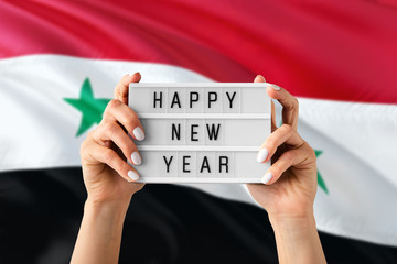 Syria New Year concept. Woman holding Happy New Year sign with hands on national flag background....