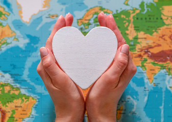 man squeezed a white heart in his palms, world map