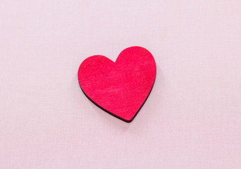 beautiful red wooden heart lies on a pink background