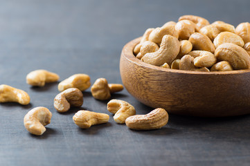 roasted salted raw cashew nuts in wooden bowl on rustic table, healthy vegetarian snack, Anacardium occidentale