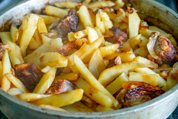 Potatoes and pork at home in a frying pan.