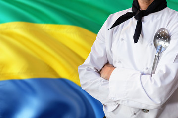 Gabon domestic food concept. Professional chef in white uniform is standing with metal spatula....