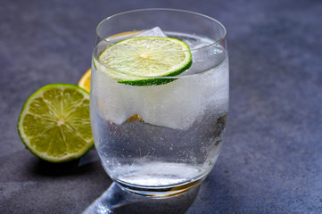  Cold drinking mineral water served in glass with ice cubes and green lime