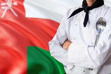 Oman domestic food concept. Professional chef in white uniform is standing with metal spatula. Copy space for text.
