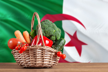 Algeria organic food concept. National flag background with basket full of vegetables on wooden...