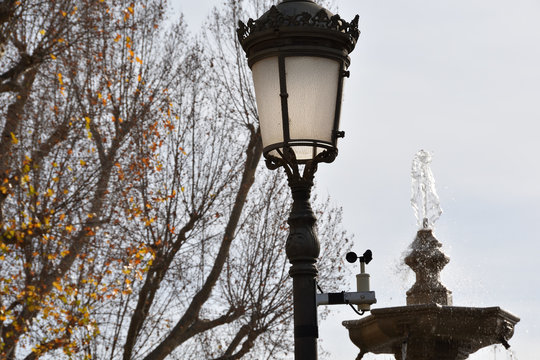 Fountain of a park in Granada next to a lamppost that has an anemometer attached