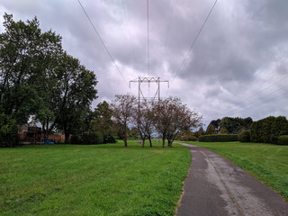 View down a paved walking trailwith trees and hydro lines on a cloudy day in Nepean sunset.