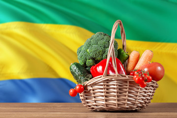 Gabon organic food concept. National flag background with basket full of vegetables on wooden...