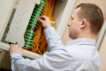 Electrician works with fiber optic cables in switchbox