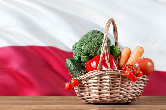Poland organic food concept. National flag background with basket full of vegetables on wooden table. Copy space for text.