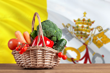 Vatican City organic food concept. National flag background with basket full of vegetables on wooden table. Copy space for text.