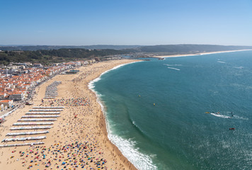 Crowded beach of Nazare from above with tourists relaxing on the sand