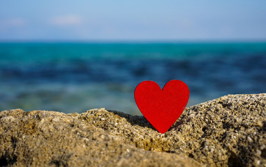 Fototapeta premium red heart on a stone in front of blue sea